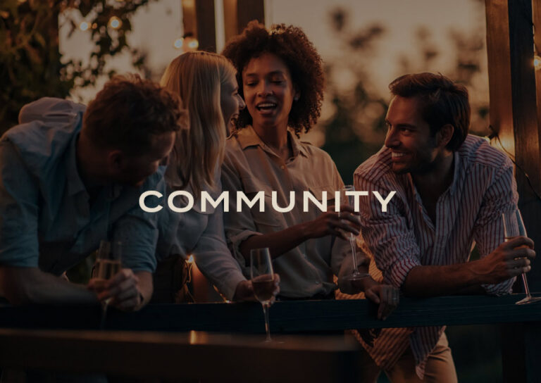 Community: friends laughing together over drinks on a deck at golden hour